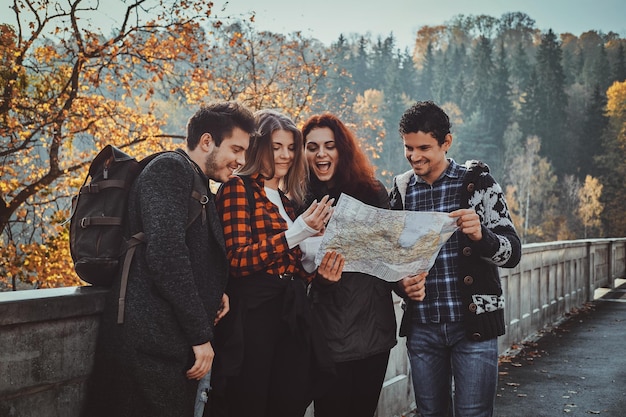 Un gruppo di giovani sta guardando la mappa dove si trovano mentre camminano nella foresta autunnale.