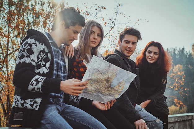 Un gruppo di giovani sta guardando la mappa dove si trovano mentre camminano nella foresta autunnale.