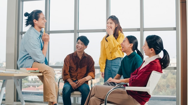 Un gruppo di giovani studenti universitari in abbigliamento casual intelligente nel campus. Amici riunione di brainstorming parlando e discutendo di idee di lavoro nuovo progetto di design in un ufficio moderno. Lavoro di squadra del collega, concetto di avvio.