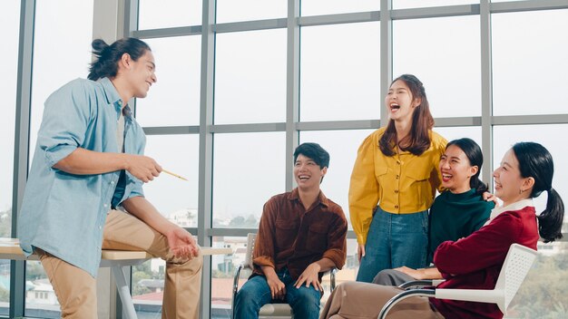 Un gruppo di giovani studenti universitari in abbigliamento casual intelligente nel campus. Amici riunione di brainstorming parlando e discutendo di idee di lavoro nuovo progetto di design in un ufficio moderno. Lavoro di squadra del collega, concetto di avvio.