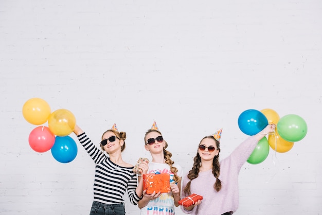Un gruppo di tre amici femminili che godono della festa con regali e palloncini