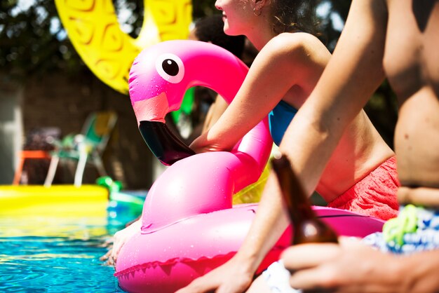 Un gruppo eterogeneo di amici che si godono l&#39;estate a bordo piscina con galleggianti gonfiabili