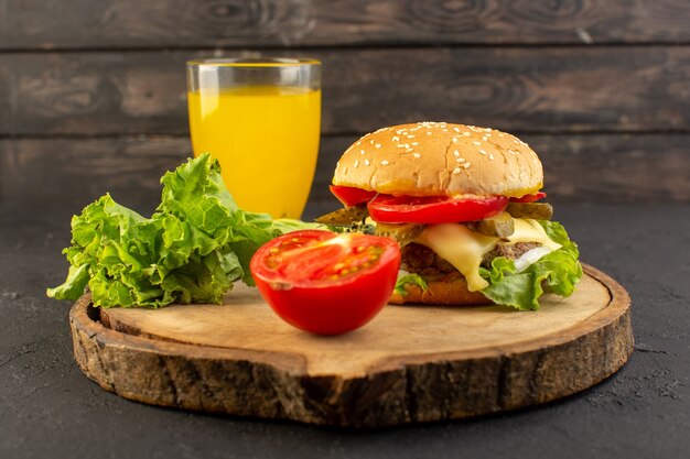 Un hamburger di pollo con vista frontale con formaggio e insalata verde insieme a succo sulla scrivania in legno e panino cibo pasto veloce