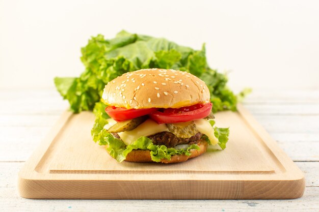 Un hamburger di pollo vista frontale con formaggio e insalata verde sullo scrittorio di legno e pasto fast-food sandwich
