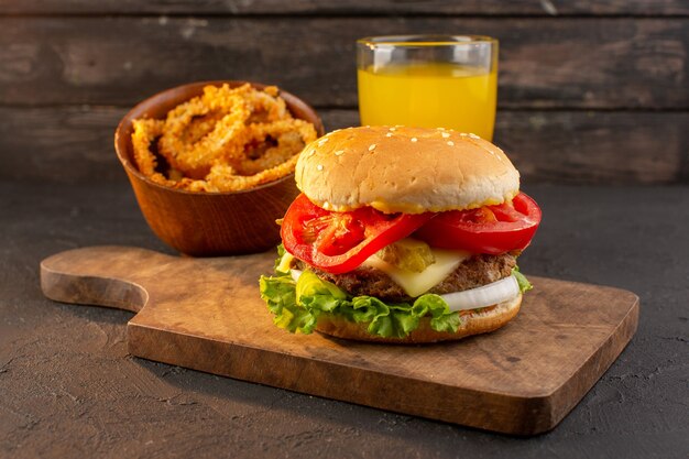 Un hamburger di pollo vista frontale con insalata di formaggio verde e succo di frutta sulla scrivania in legno e un pasto fast-food sandwich