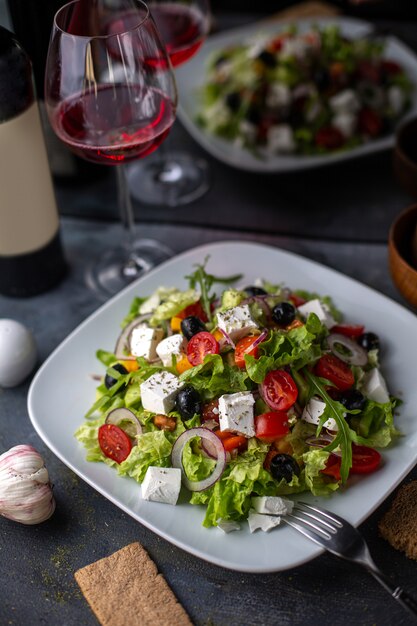 Un'insalata di verdure affettata dell'insalata della Grecia di vista frontale con i pomodori cetrioli formaggio bianco e olive dentro le verdure bianche di vitamine del piatto