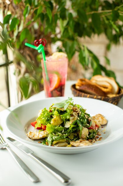 Un'insalata fresca di vista alta vicina della parte anteriore con le verdure e le verdure affettate dentro il piatto bianco sul pavimento bianco