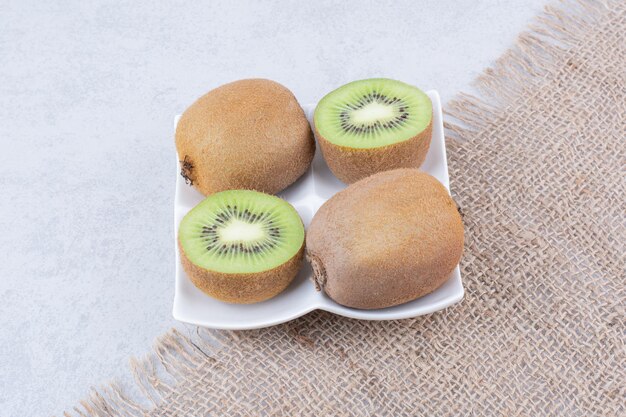 Un kiwi a fette nel piatto bianco su tela di sacco