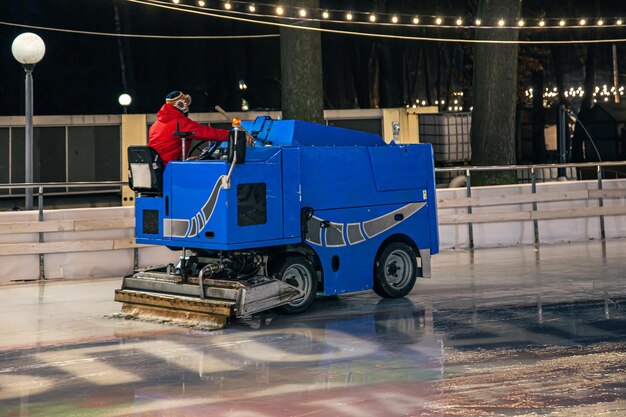 Un lavoratore dello stadio pulisce una pista di pattinaggio su una moderna macchina per la pulizia del ghiaccio blu