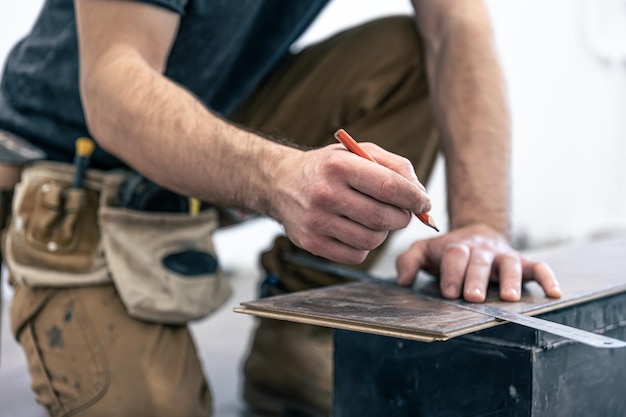 Un lavoratore di sesso maschile mette il pavimento in laminato sul pavimento