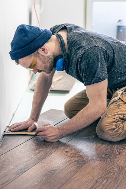 Un lavoratore di sesso maschile mette il pavimento in laminato sul pavimento