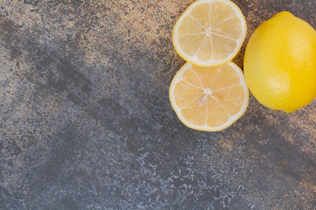 Un limone intero con fette sulla superficie della pietra