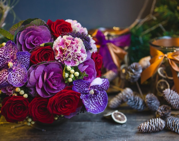 Un mazzo di rose rosse, fiori rosa e viola con foglie sul tavolo di Natale