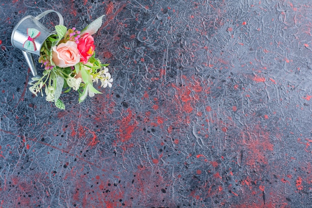 Un minuscolo annaffiatoio metallico pieno di un bel mazzo di fiori.