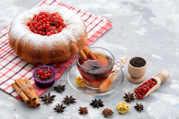 Un mirtillo rosso fresco di vista superiore aspro e pastoso con tè rotondo della torta e cannella sul colore fresco dello scrittorio bianco