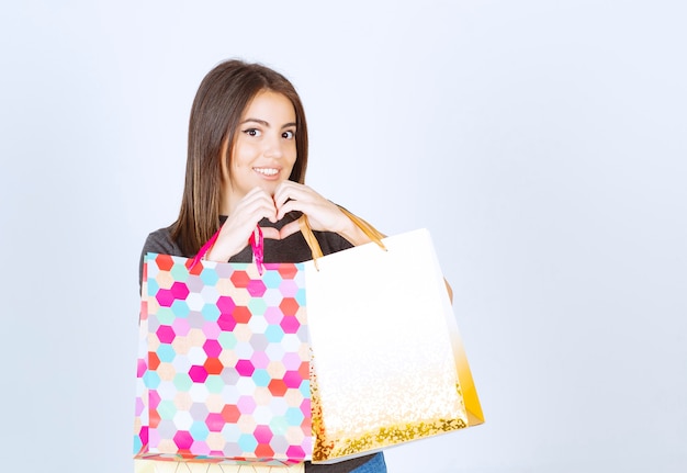 Un modello di donna felice che tiene un sacco di borse della spesa su sfondo bianco.