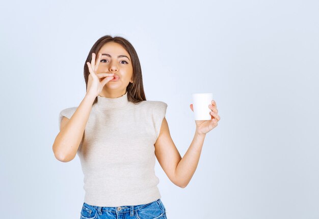 Un modello di donna sorridente che mostra un bicchiere di plastica e in posa.