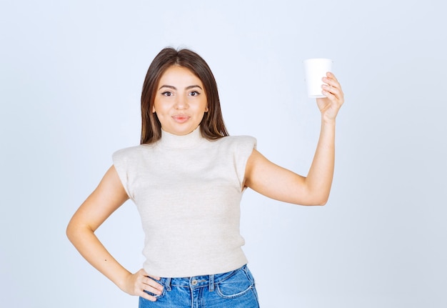 Un modello di donna sorridente che mostra un bicchiere di plastica e in posa.