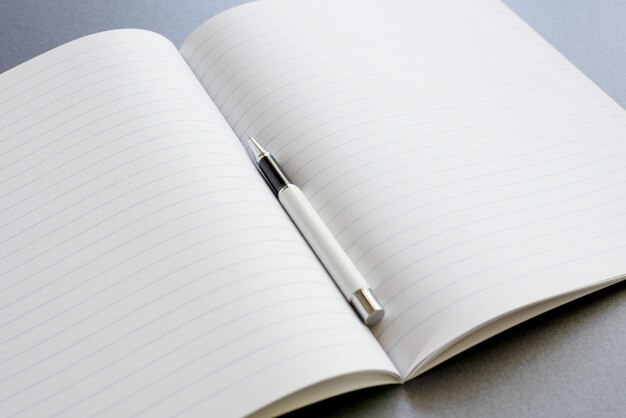 Un notebook aperto con una penna su sfondo grigio scuro, lavoro di scena o studio.