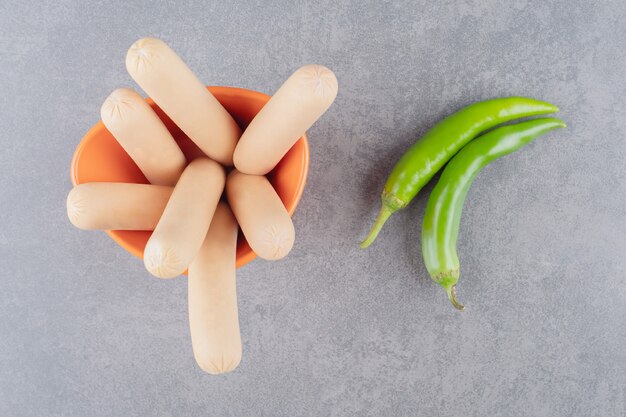 Un piatto arancione di salsicce bollite con peperoncino