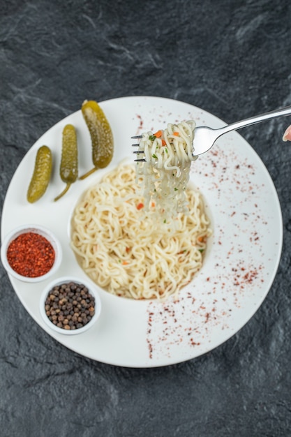 Un piatto bianco con deliziose tagliatelle e cetriolini sottaceto.