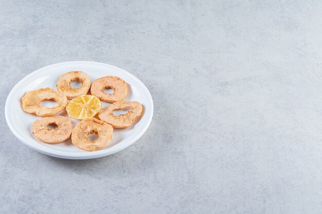 Un piatto bianco con frutta secca sana su sfondo marmo.