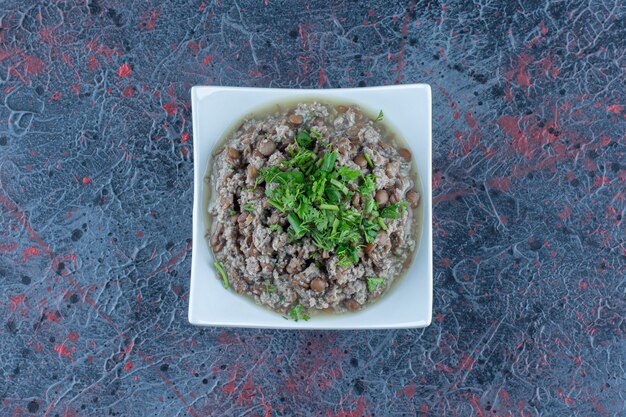 Un piatto bianco di carne tritata con piselli ed erbe aromatiche.