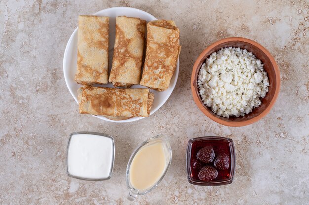 Un piatto bianco di gustose crepes e marmellata di fragole