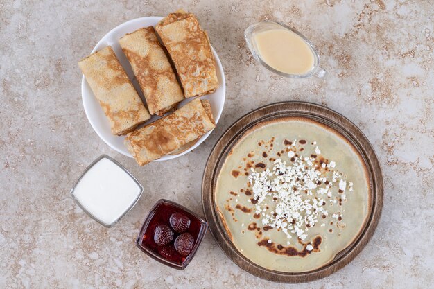 Un piatto bianco di gustose crepes e marmellata di fragole