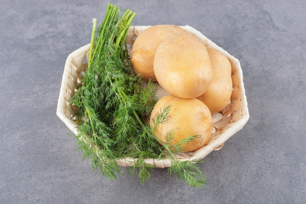 Un piatto bianco di patate crude con aneto fresco