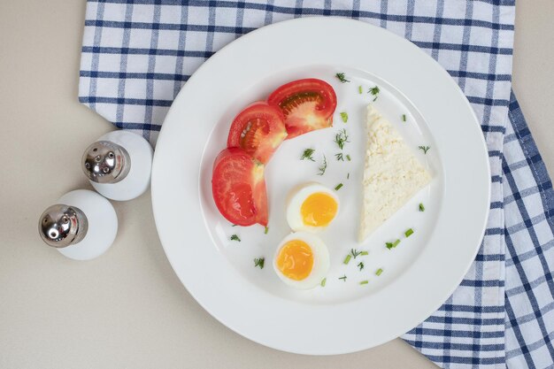 Un piatto bianco di pomodoro a fette e uovo sodo.