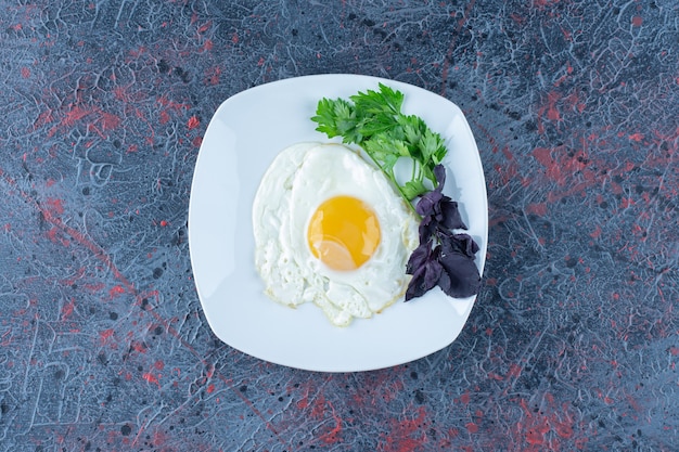 Un piatto bianco di uova fritte con erbe aromatiche.