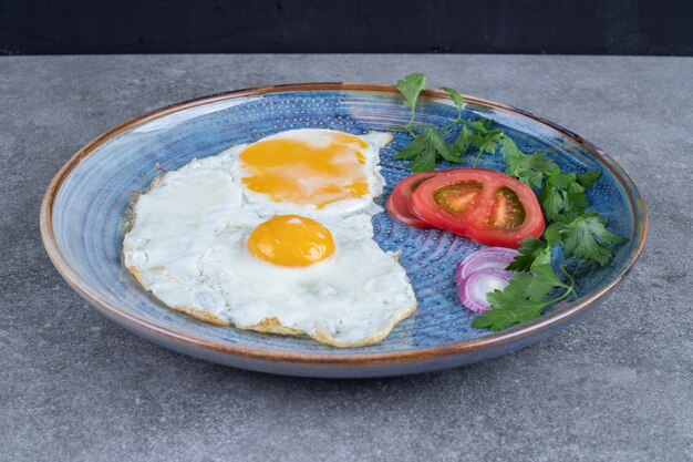 Un piatto con uova fritte e verdure a fette. Foto di alta qualità