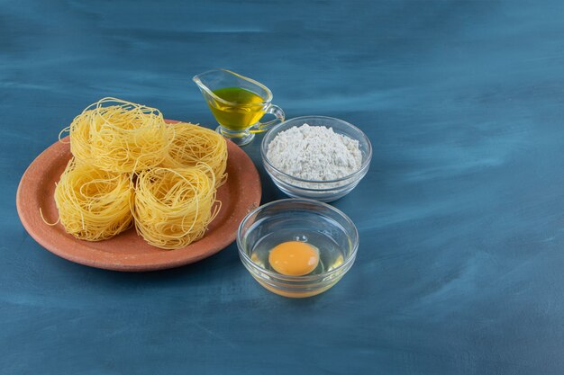 Un piatto di argilla di pasta grezza nido secco su uno sfondo blu scuro.