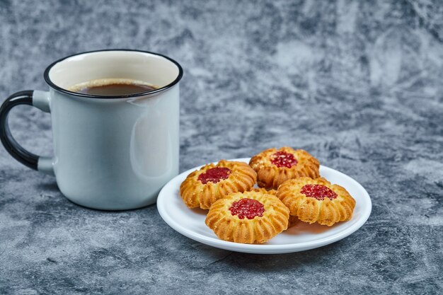 Un piatto di biscotti e caffè sul tavolo di marmo.