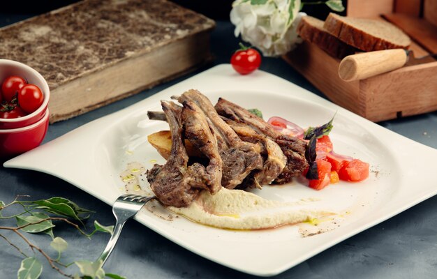 un piatto di costolette di agnello alla griglia con purea e patate fritte