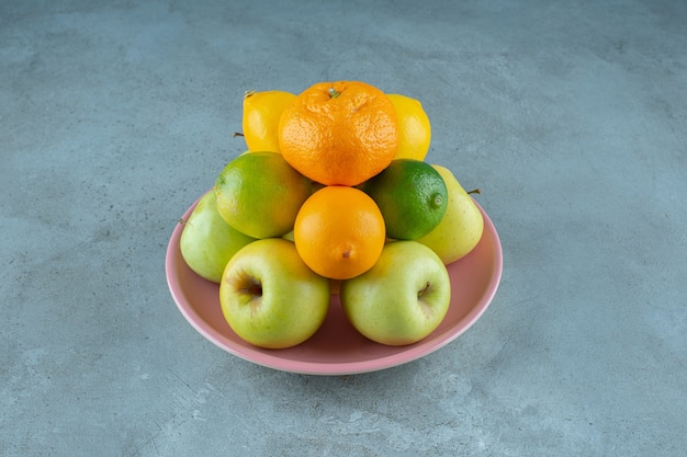 Un piatto di frutta varia, sullo sfondo marmoreo. Foto di alta qualità