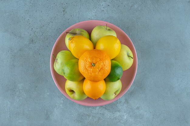 Un piatto di frutta varia, sullo sfondo marmoreo. Foto di alta qualità