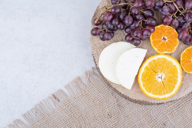 Un piatto di legno con formaggio a fette e frutta. Foto di alta qualità