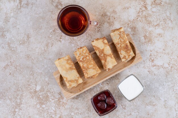 Un piatto di legno con frittelle e una tazza di tè