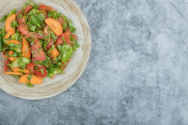 Un piatto di legno di deliziosa insalata di verdure.