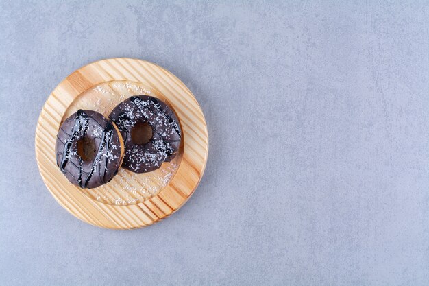 Un piatto di legno di deliziose ciambelle al cioccolato con spruzza.