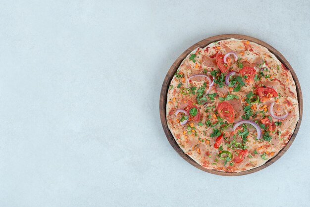 Un piatto di legno di pane pita con pomodoro e cipolla a fette.