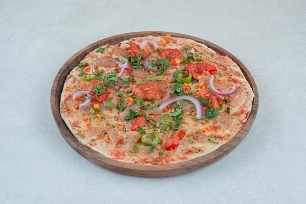 Un piatto di legno di pane pita con pomodoro e cipolla a fette.