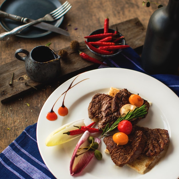 Un piatto di pezzi di bistecca di agnello guarnito con verdure e rosmarino