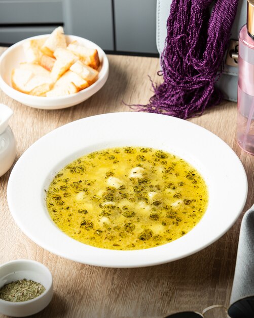 Un piatto di zuppa di gnocchi dushbara azeri guarnito con foglie di menta essiccate