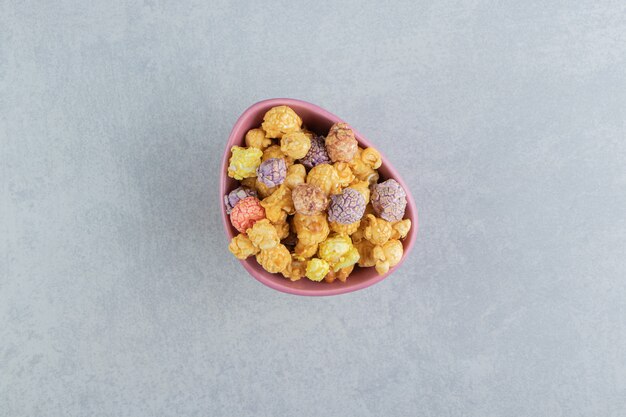 Un piatto fondo rosa di popcorn multicolori dolci.