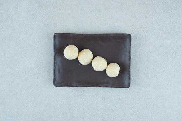 Un piatto nero con alcuni deliziosi biscotti rotondi.