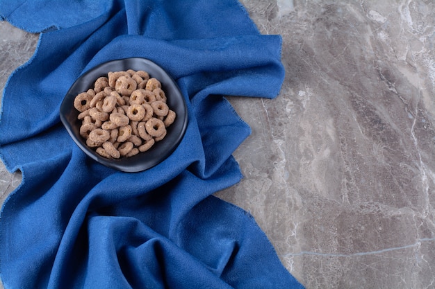 Un piatto nero di anelli di cereali al cioccolato sani per la colazione.