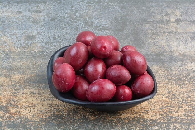 Un piatto scuro di deliziosi frutti su sfondo bianco. Foto di alta qualità